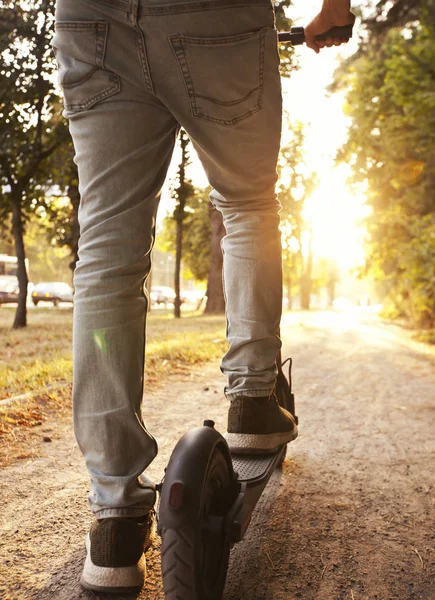 El joven está montando en el scooter eléctrico a través de la incluso — Foto de Stock