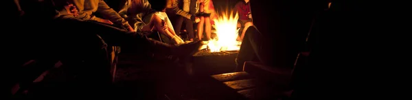 Le groupe d'amis sont assis près du feu de joie dans la nuit un — Photo