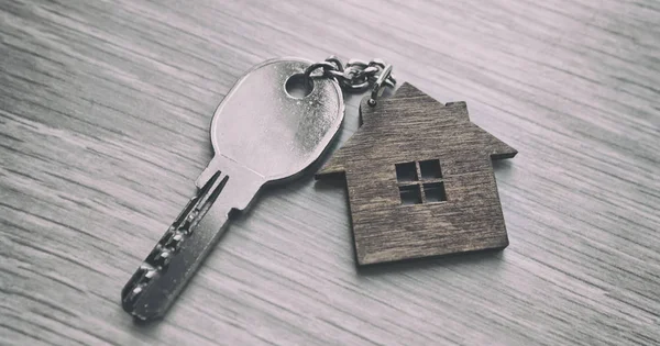 Metalowy klucz od drzwi z drewnianą drobiaztką w kształcie domu jest — Zdjęcie stockowe