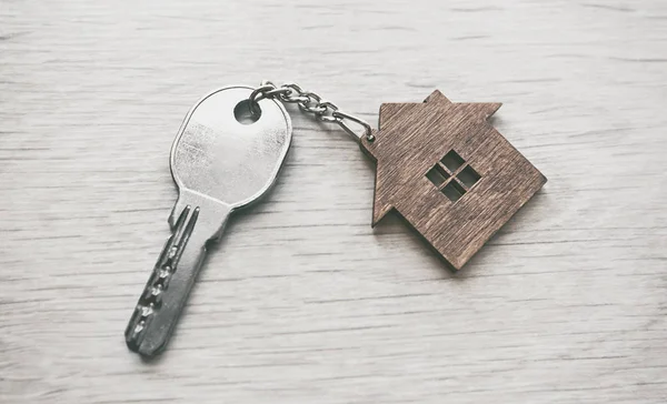 Металлический ключ от двери с деревянной безделушкой в форме дома — стоковое фото