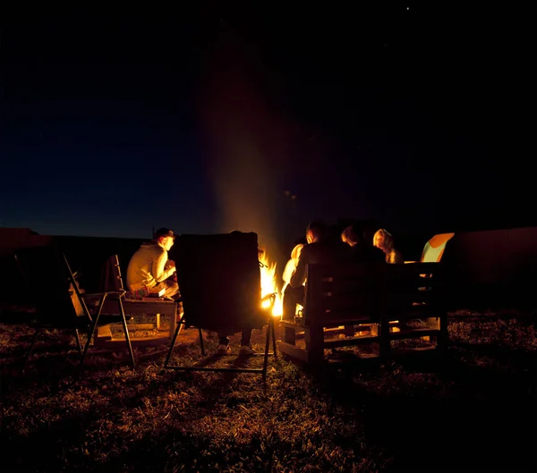友人のグループは、夜にたき火の近くに座っています — ストック写真