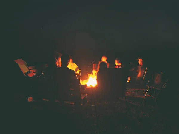 O grupo de amigos estão sentados perto da fogueira na noite um — Fotografia de Stock