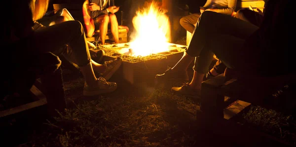 Le groupe d'amis sont assis près du feu de joie dans la nuit un — Photo