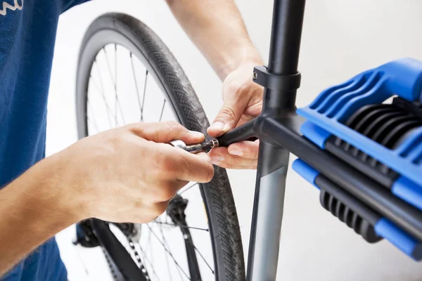 The mechanic is fixing the road bicycle in his workshop — Stock Photo, Image