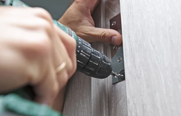 O homem está instalando a parte da porta de madeira pelo parafuso — Fotografia de Stock