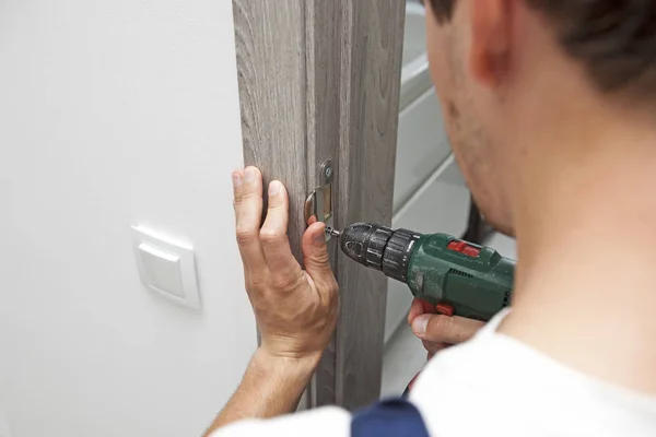 El hombre está instalando la parte de la puerta de madera por el tornillo — Foto de Stock