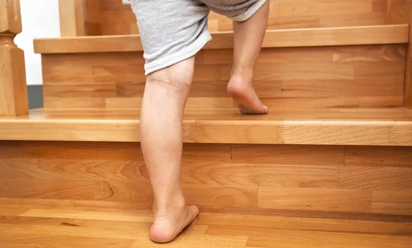 El niño está subiendo por las escaleras de madera en casa. — Foto de Stock