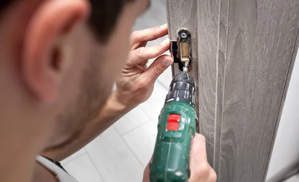 El hombre está instalando la parte de la puerta de madera por el tornillo —  Fotos de Stock