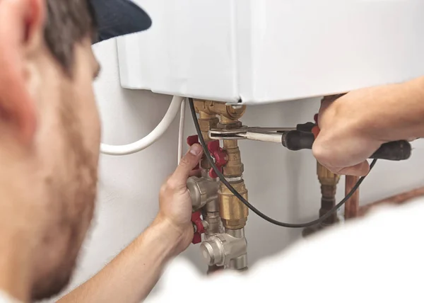 El hombre está instalando el sistema de calefacción en la casa y checkin —  Fotos de Stock