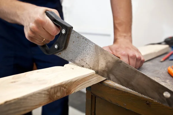 El hombre está cortando el tablón de madera por sierra — Foto de Stock