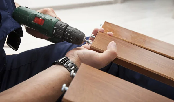 El hombre está montando muebles de madera en casa — Foto de Stock