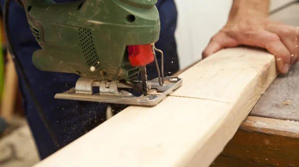 O homem está cortando a prancha de madeira por quebra-cabeças — Fotografia de Stock