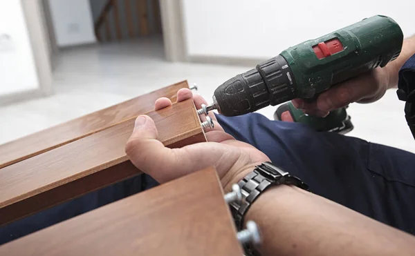 O homem está montando móveis de madeira em casa — Fotografia de Stock