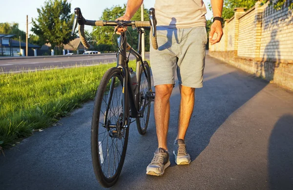 El joven con bicicleta está caminando por la carretera. — Foto de Stock