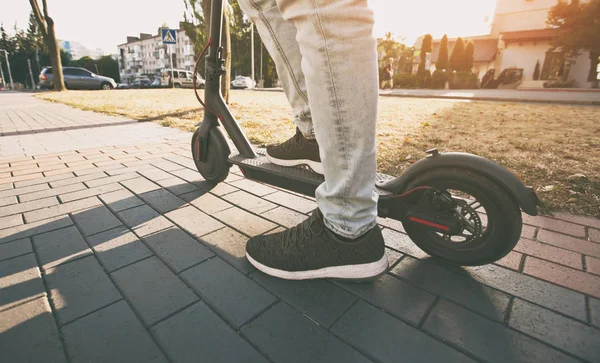 El joven está montando en el scooter eléctrico a través de la incluso — Foto de Stock