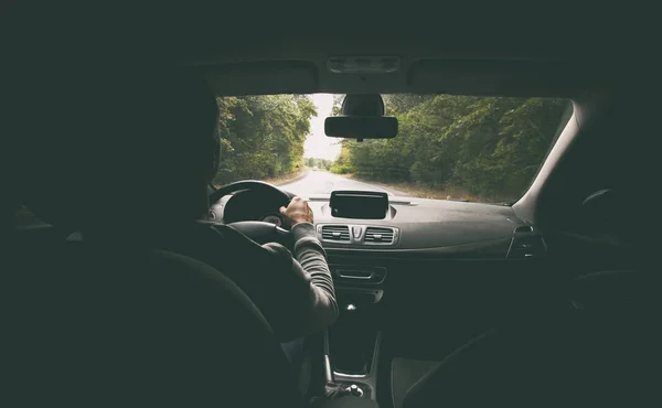 O jovem dirigindo o carro moderno na estrada de asfalto — Fotografia de Stock