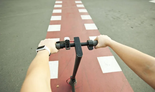 La joven está montando en el scooter eléctrico a través de la ev —  Fotos de Stock