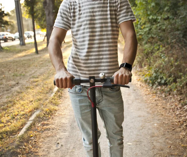 O jovem está montando na scooter elétrico através do mesmo — Fotografia de Stock