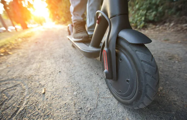 The young man is riding on the electric scooter through the even — Stock Photo, Image