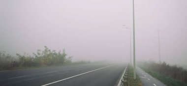 Şehrin dışındaki asfalt yol ve üzerindeki kalın sis. 
