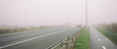 Şehrin dışındaki asfalt yol ve üzerindeki kalın sis. 