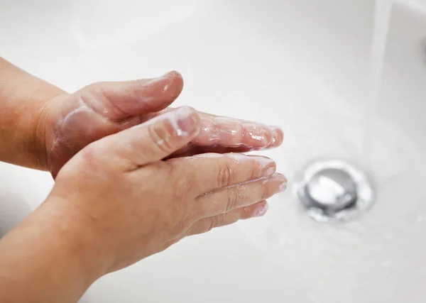 Çocuk suyun altında ellerini sabunla yıkıyor. — Stok fotoğraf