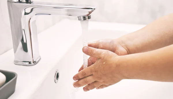 The boy is washing his hands with soap under the water — Stock Photo, Image