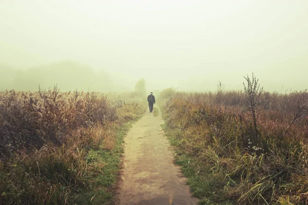 Ten muž kráčí po venkovské cestě na louce v — Stock fotografie