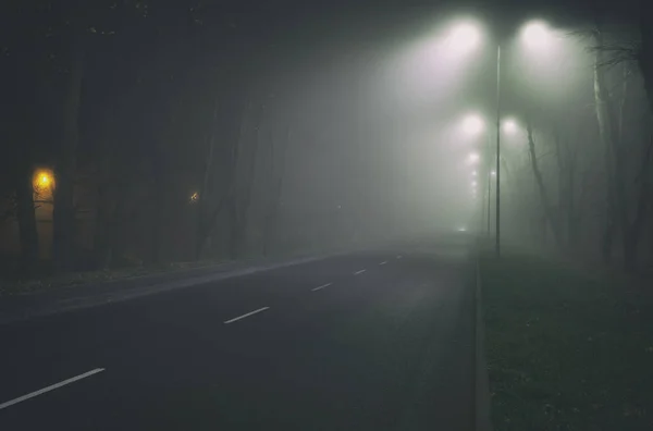 La espesa niebla sobre el camino de asfalto en la noche en la ciudad — Foto de Stock