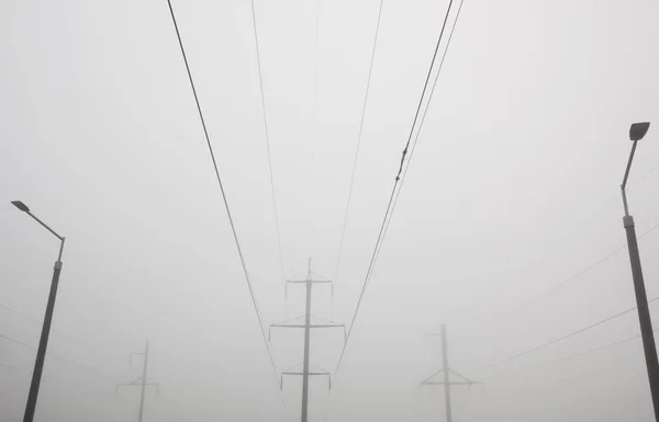 The electric pole and wires in front of gray foggy cloud. Concep — Stock Photo, Image