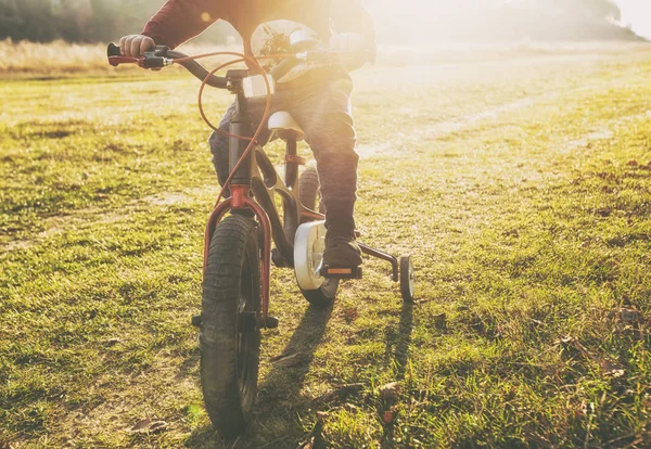 De kleine jongen rijdt op de fiets door het land weg in — Stockfoto