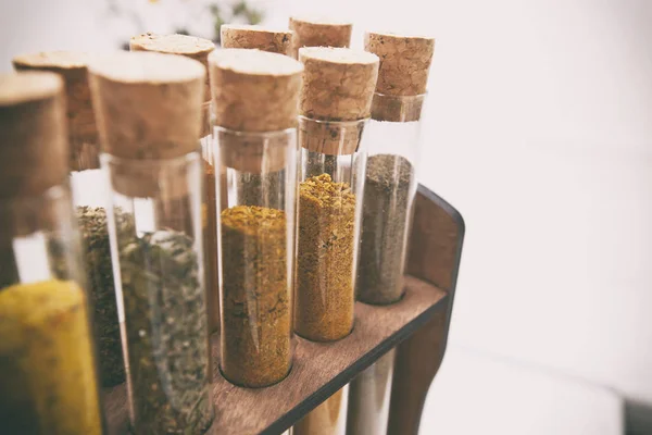 Glass flasks with different type of spices on the kitchen table — Stock Photo, Image