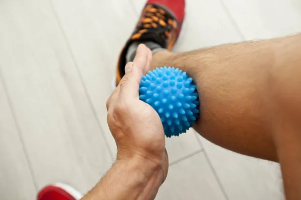 The man is massaging his leg by massage ball at home — Stock Photo, Image