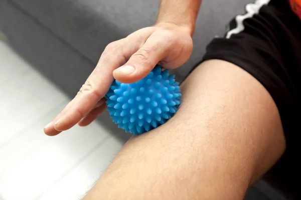 O homem está massageando sua perna por bola de massagem em casa — Fotografia de Stock