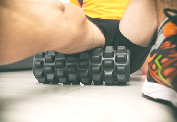 The man is massaging his muscles by the foam roller — Stock Photo, Image