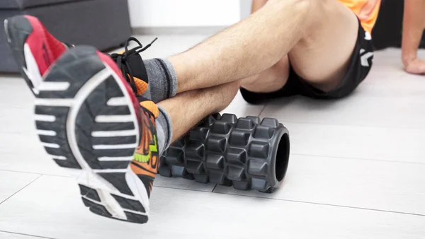 The man is massaging his muscles by the foam roller — Stock Photo, Image