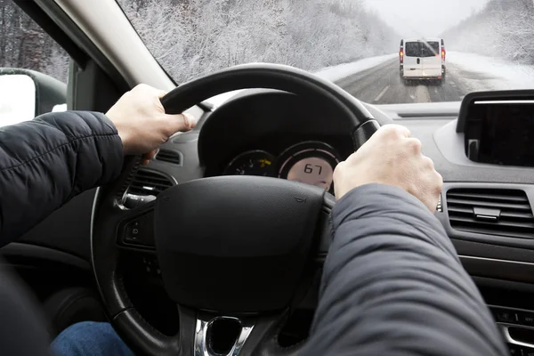 Den unge mannen kör på sin bil genom sne snöiga vägen — Stockfoto