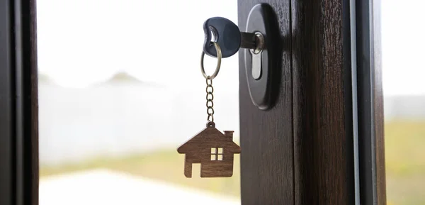 Una baratija en forma de casa en la llave en la cerradura —  Fotos de Stock