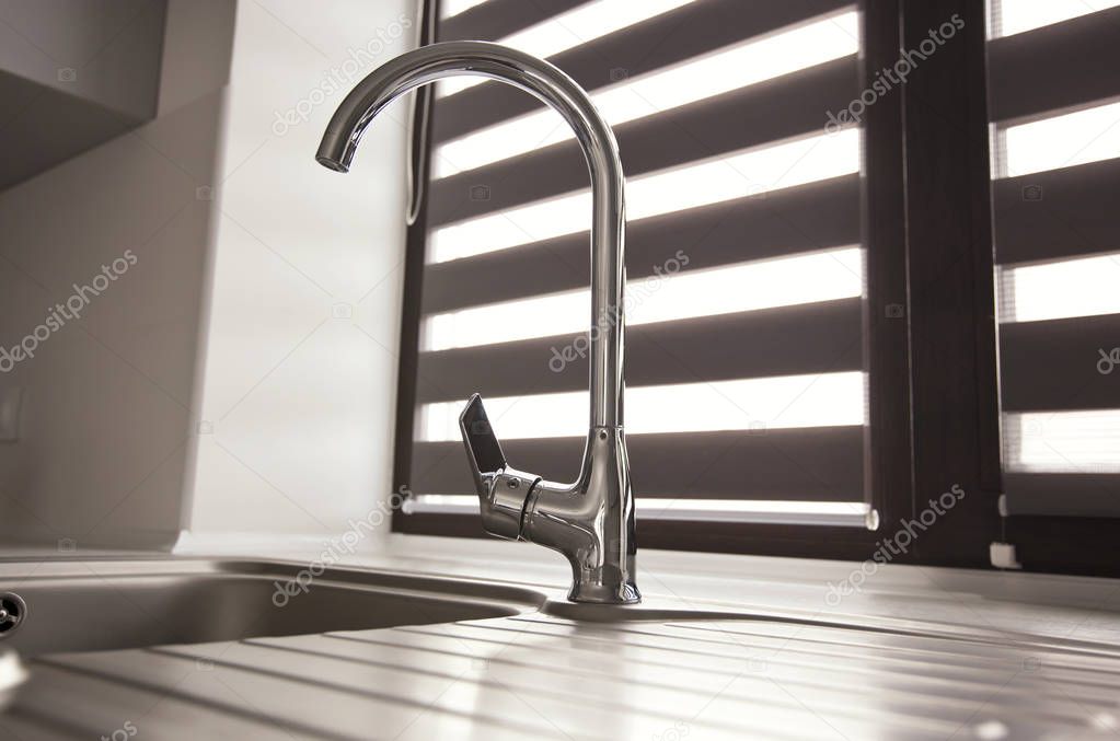 Metal faucet in the modern gray kitchen