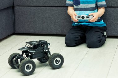 Çocuk joystick 'i tutuyor ve radyo kumandalı arabayla oynuyor.