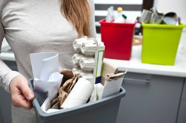 Kadın plastik kutunun tamamını çeşitli kağıt çöplerle doldurmuş.