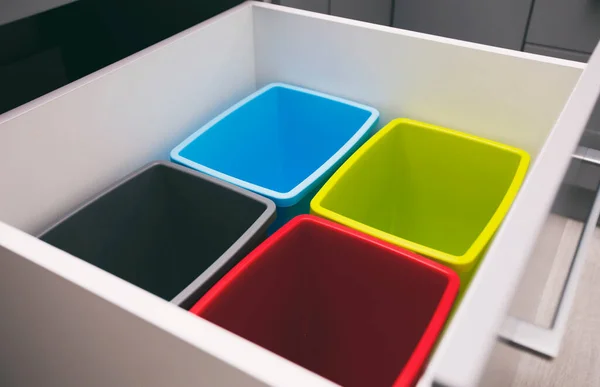 Four empty plastic trash bins in the shelf in the kitchen for sorting garbage