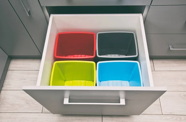 Four empty plastic trash bins in the shelf in the kitchen for sorting garbage