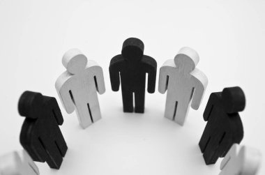 Ahşap şekilli siyah beyaz insan figürleri daire çiziyor. Arkadaşlık kavramı, takım çalışması ve ırkçılık eksikliği.