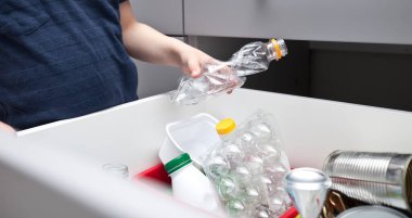 Çocuk çöpü, çöpleri ayıklamak için dört farklı çöp kutusundan birine atıyor.. 