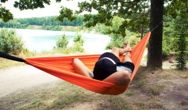 Adam kamptaki hamakta dinleniyor ve dinleniyor.