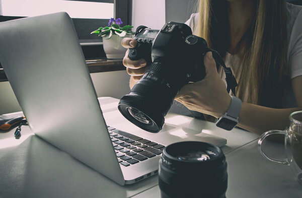 Фотограф работает за ноутбуком и много фотооборудования лежит на столе