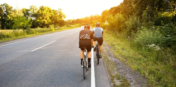 Twee Fietsers Rijden Door Asfaltweg Bij Zonsondergang — Stockfoto