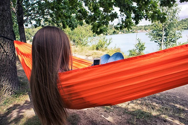 Femme Refroidit Relaxe Dans Hamac Tout Parcourant Téléphone Regardant Lac — Photo