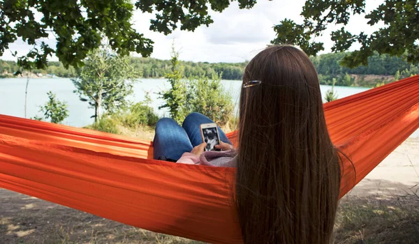 Femme Refroidit Relaxe Dans Hamac Tout Parcourant Téléphone Regardant Lac — Photo